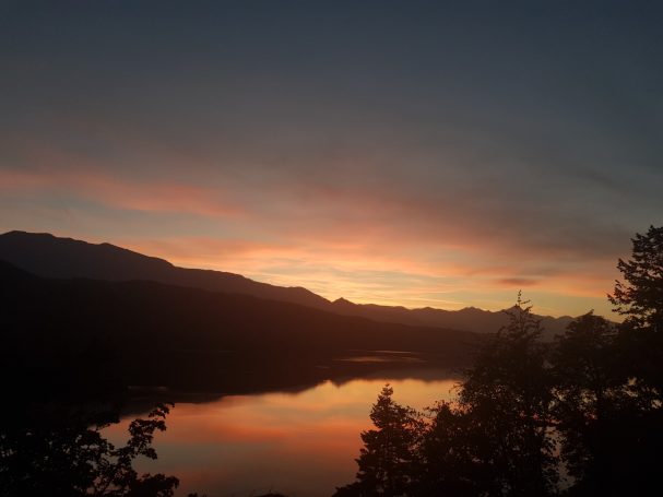 Sonnenuntergang mit Reflexionen auf einem See mit Bergpanorama