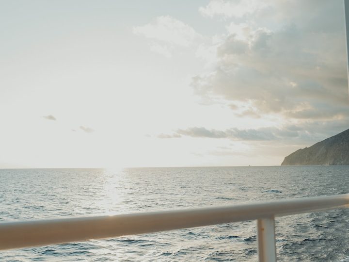 Heller Sonnenuntergang über dem Meer mit Küstenlinie im Hintergrund.